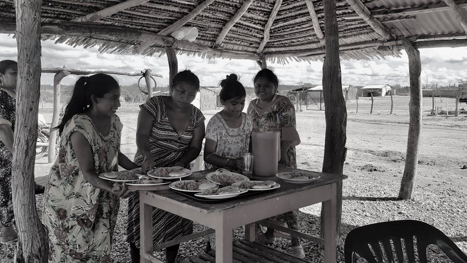 Yerel halk ile köy yemeği masasında sohbet eden turistler ve geleneksel yemekler