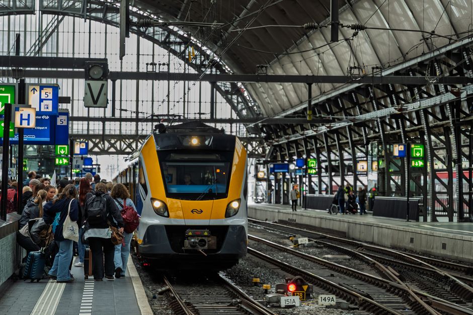 Avrupa tren istasyonu platformunda yolcular bilet kontrolü yapıyor ve sefer tabelalarını inceliyor.