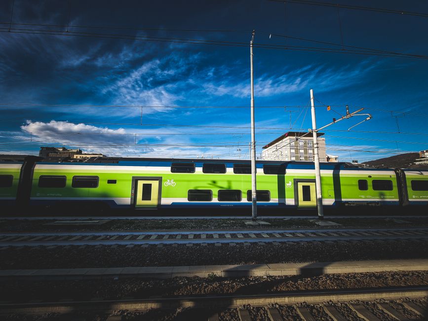 İstasyon platformunda düşük karbonlu tren yolculuğunu simgeleyen yolcu ve tren maketi